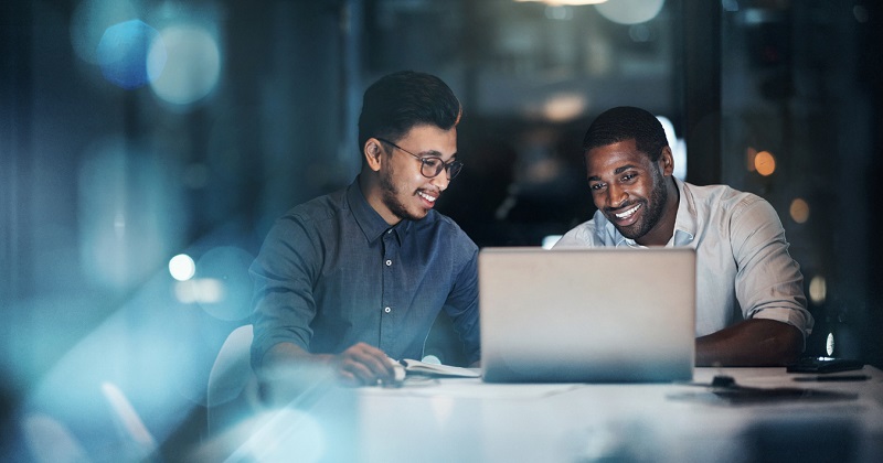 Shot of two young businessmen using a laptop during a late night meeting in a modern office