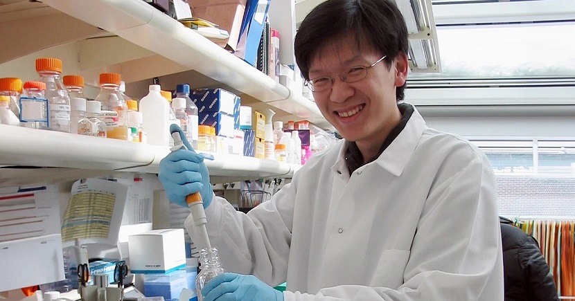 Dr Tan in a research lab holding lab equipments